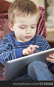 Boy Sitting On Sofa And Playing With Digital Tablet