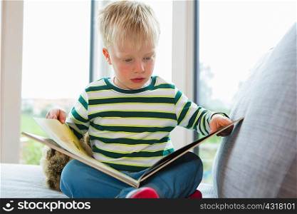 Boy sitting on sofa reading a book