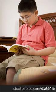 Boy sitting on the bed and reading a book