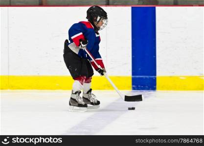 Boy skating with the puck at ice hockey practice