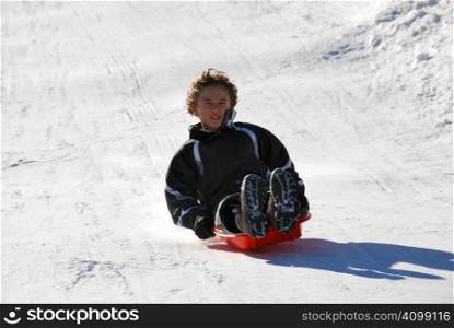 boy sledding fast down the hill with snow background