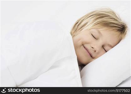 Boy sleeping in bed and smiling. Lovely little boy peacefully sleeping in a bed smiling seeing a dream
