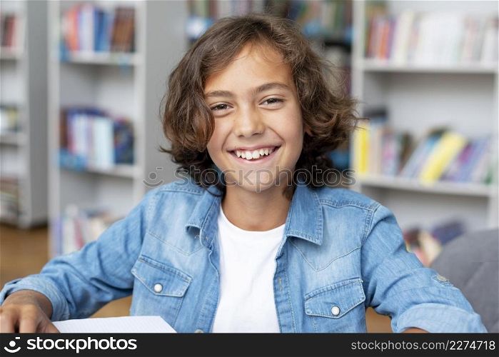 boy smiling while sitting library