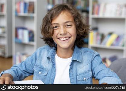 boy smiling while sitting library