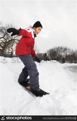 Boy snowboarding in snow.