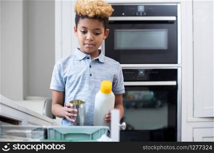 Boy Sorting Recycling Into Kitchen Bin At Home