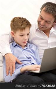Boy spending time with laptop, happy father embracing and looking at him