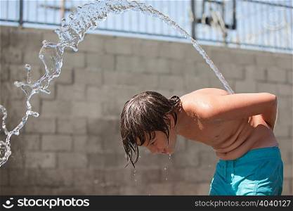 Boy squirting water over his back