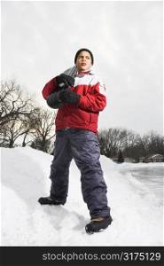 Boy standing holding snowboard in snow.