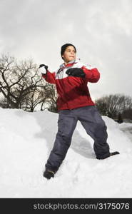 Boy standing in snow throwing snowball.