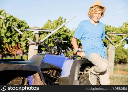 Boy standing next to truck in vineyard. Boy wearing hat standing next to truck in vineyard