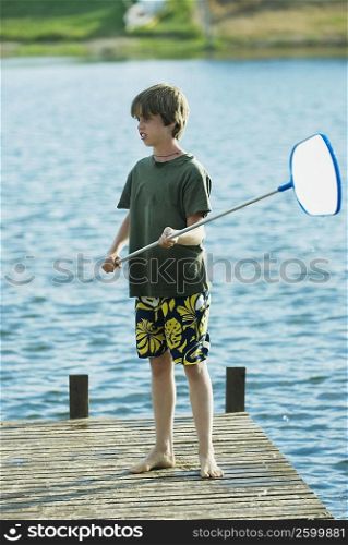 Boy standing on a pier and holding a fishing net