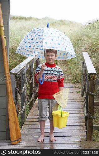 Boy standing on footbridge with umbrella