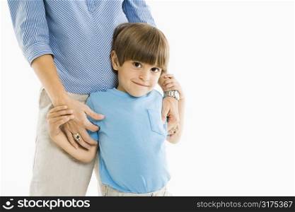 Boy standing with mother against white background.