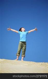 boy stands on sand and looks upwards