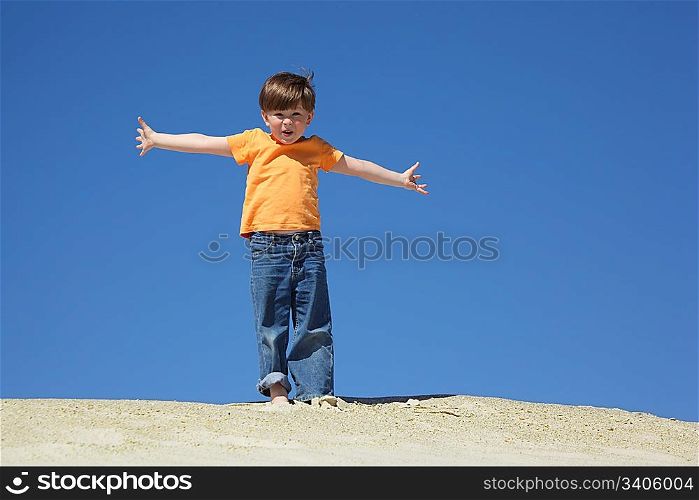 boy stands on sand with wide hands