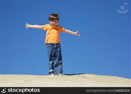 boy stands on sand with wide hands