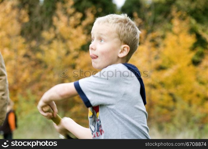 Boy swinging a cricket bat and sticking his tongue out