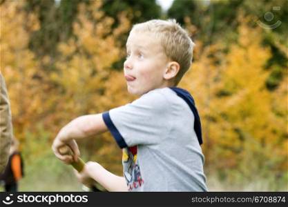 Boy swinging a cricket bat and sticking his tongue out