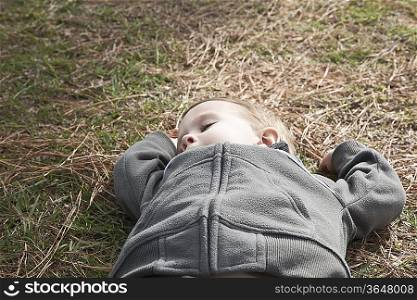 Boy taking a nap on grass, high angle view