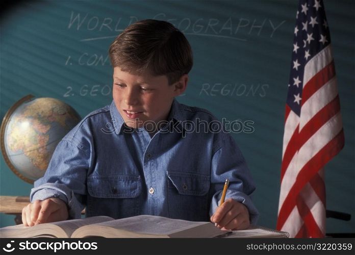 Boy Taking Notes In Geography Classroom
