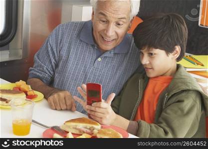 Boy teaching his grandfather how to use a mobile phone
