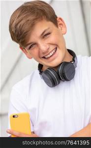 Boy teenager teen male child outside using his mobile cell phone and bluetooth wireless headphones for music or social media
