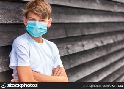 Boy teenager teen male child wearing a face mask outside during the Coronavirus COVID-19 virus  pandemic