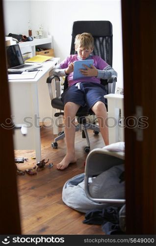 Boy Using Digital Tablet In Bedroom