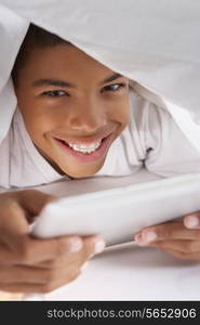 Boy Using Digital Tablet Under Duvet