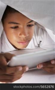 Boy Using Digital Tablet Under Duvet