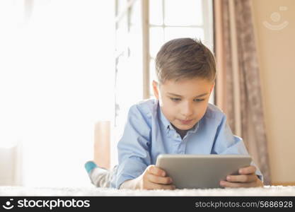 Boy using digital tablet while lying on floor at home