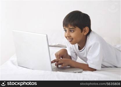 Boy using laptop in bed