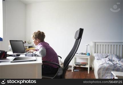 Boy Using Laptop In Bedroom