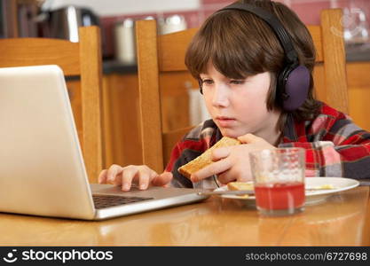 Boy Using Laptop Whilst Eating Breakfast