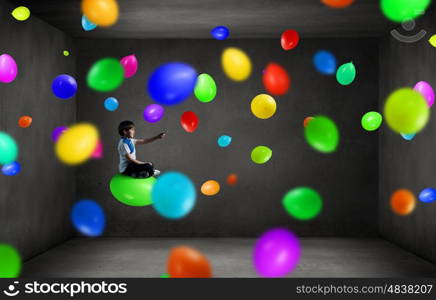 Boy using modern technologies. Cute school boy sitting on balloon and using his smartphone