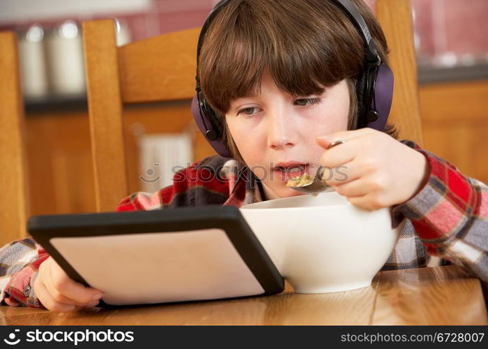 Boy Using Tablet Computer Whilst Eating Breakfast