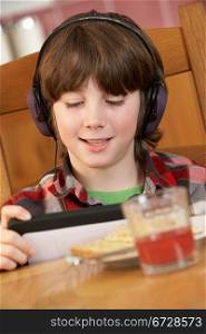 Boy Using Tablet Computer Whilst Eating Breakfast