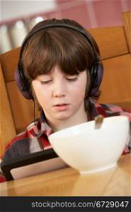 Boy Using Tablet Computer Whilst Eating Breakfast
