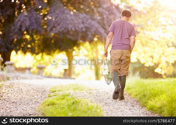 Boy Walking Along Path Carrying Fishing Net And Jar