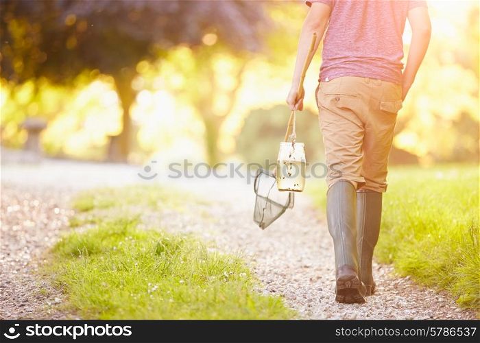 Boy Walking Along Path Carrying Fishing Net And Jar