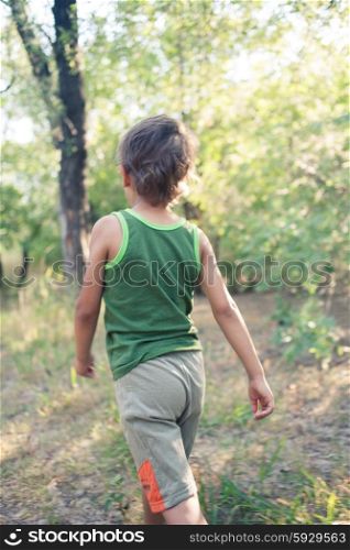 Boy walking in a forest from back side view