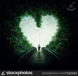 Boy walking on a bridge through the heart shape woods, following the light. Follow your heart concept