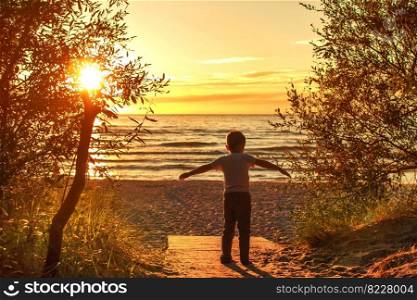 boy walking on the beach in the sand at sunset