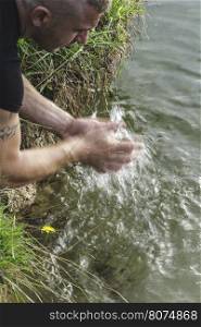 Boy wash his hands in a lake. Close up