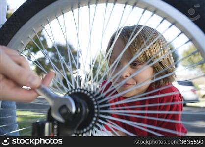 Boy watching father fix bicycle tyre