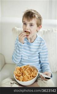 Boy watching TV while eating wheel shape snack pellets