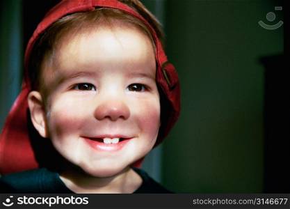 Boy Wearing An Oversized Red Hat And Smiling