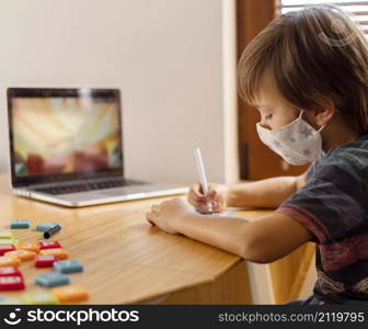 boy wearing medical mask attending virtual school