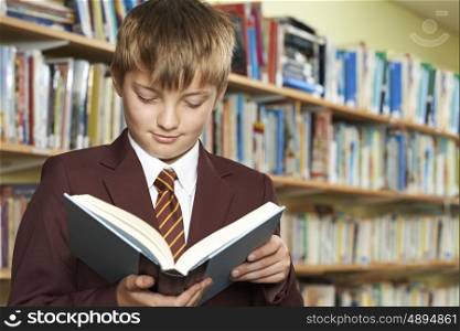 Boy Wearing School Uniform Reading Book In Library
